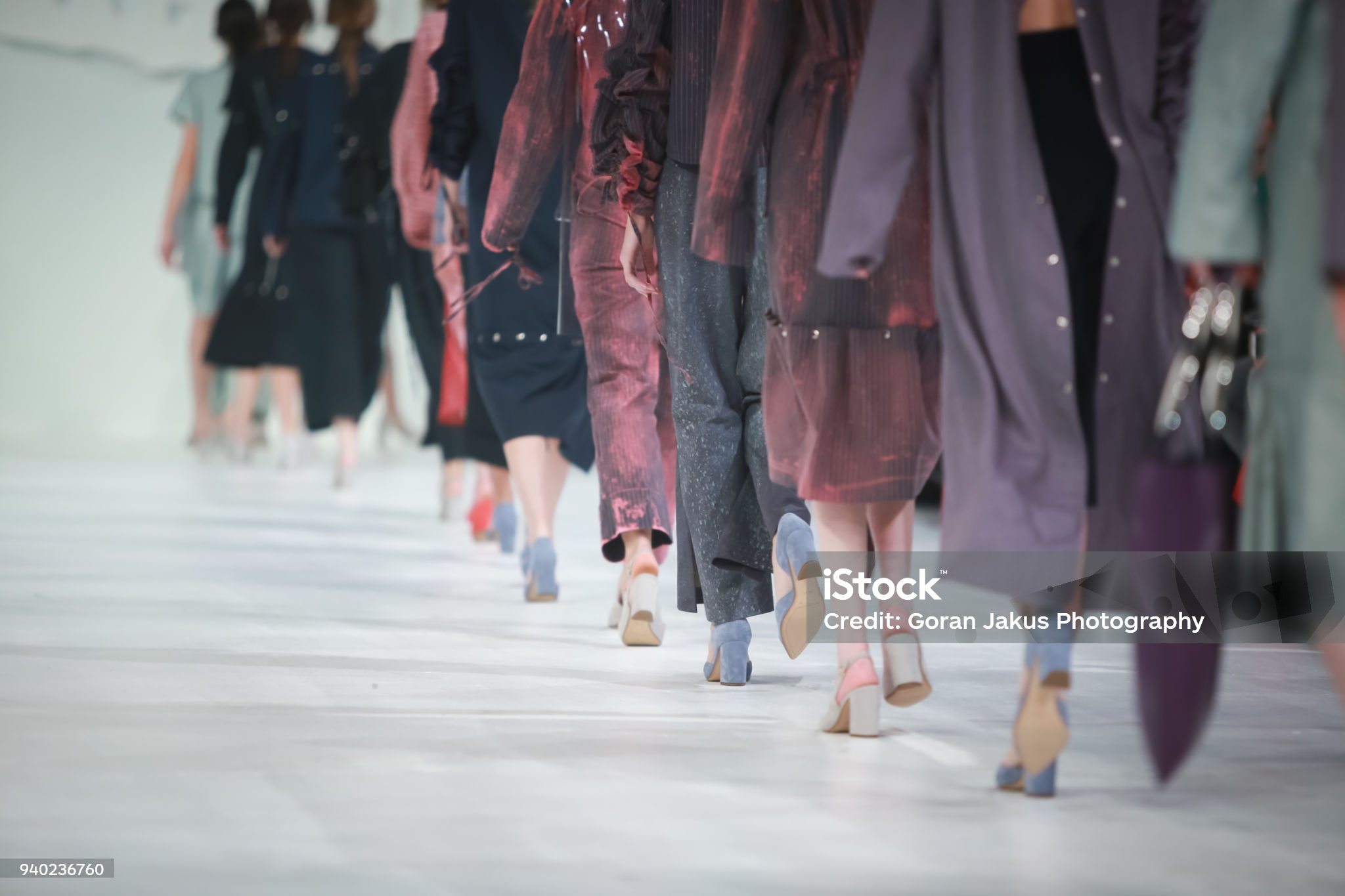 Models on a white runway in plum, grey, and navy tailored looks
